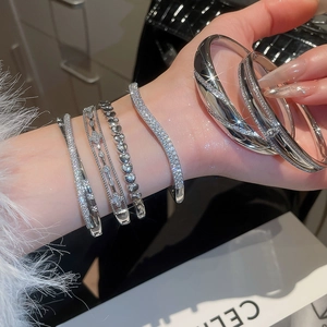 Detail shot of silver-toned 18k plated bangles with zircon heart and geometric links