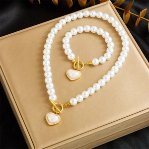 Macro detail of gold-plated pearl jewelry set with heart pendant and toggle closure