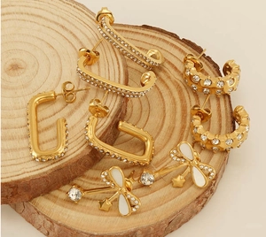 Détails de diverses boucles d'oreilles plaquées or 18 carats avec zircon sur bois naturel