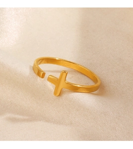 Macro shot of gold stainless steel cross ring on champagne silk background