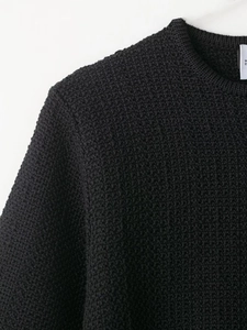 Detail of black knit sweater neck with round collar and textured fabric surface