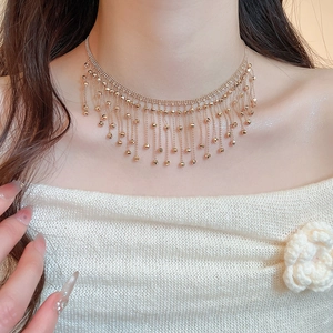 Close-up of golden tassel necklace on model highlighting dynamic metallic fringe details