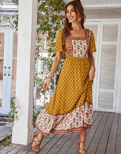 Detail of yellow floral bohemian tiered dress with square neckline and flowy skirt