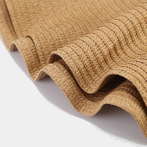 Detail of hand-woven straw hat edge with shimmering tinsel and wavy brim design