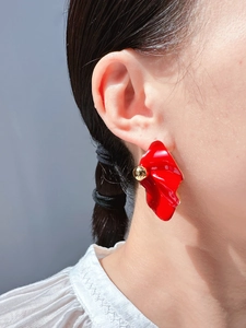 Detail of red floral earrings with gold bead on model showing size and modern style