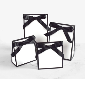 Détail macro de sacs cadeaux blancs avec bordure noire et nœuds en satin élégants