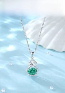 Macro detail of S925 silver gourd pendant featuring green gemstone on blue water waves