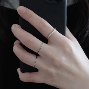 Close-up of three minimalist 925 silver rings worn on fingers with mirror selfie style