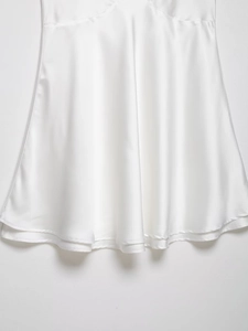 Détail de la robe en satin blanc montrant la texture de soie et la couture fine