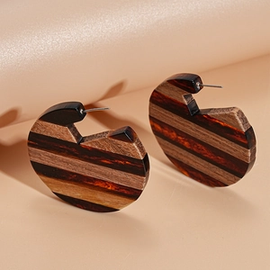Detail of resin and wood geometric hoop earrings with striped texture and silver needle