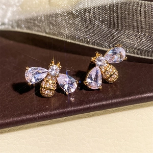 Macro shot of gold-plated bee earrings with shimmering cubic zirconia stones details