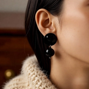 Close-up of black acrylic round drop earrings worn by a model in a lifestyle setting