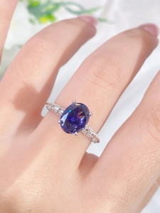 Macro shot of silver ring featuring oval purple gemstone and pavé diamond details
