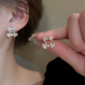 Macro detail of silver heart-shaped crystal earrings with four-diamond petal structure