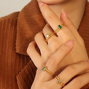Gold vintage ring set featuring emerald green and white zircons worn on hand