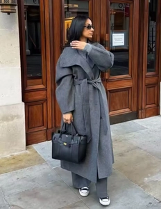 Vista street style di un lungo cappotto grigio in lana con ampi revers e cintura