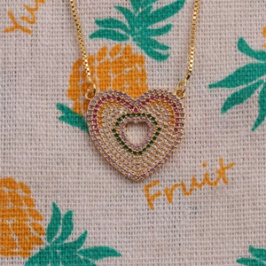 Macro shot of heart pendant with multi-color zircon inlay on gold plated box chain necklace