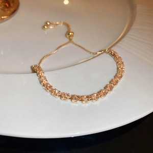 Detail of adjustable golden bracelet featuring square champagne zirconia on white plate