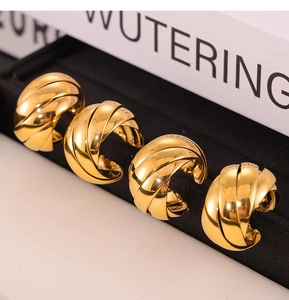 Macro shot of twisted gold titanium steel hoop earrings arranged on black velvet padding