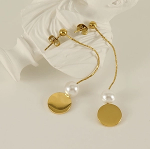 Detail of 18K gold titanium fringe earrings with pearls on white display stand
