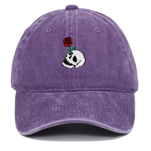 Close-up of a skull and rose embroidery on a washed purple cotton baseball cap