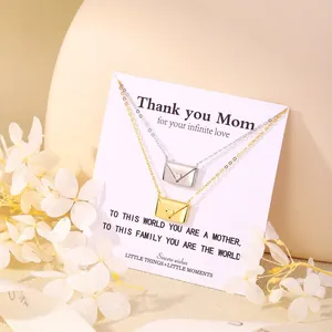 Detailed view of gold and silver envelope pendant necklaces with tiny heart on display card