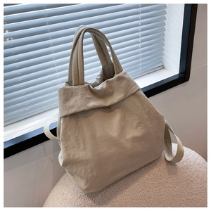 Close-up of lightweight beige nylon tote bag with soft texture on white plush surface