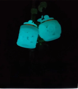 Luminous stone pendants in hollow lantern shape glowing brightly in the dark after light absorption