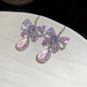 Detailed close-up of bow earrings with pink water-drop gemstone and zircon tassels