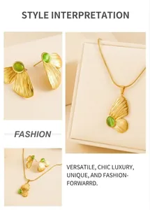 Detail view of gold butterfly wings jewelry set with green cat eye stones and snake chain
