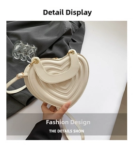 Detail der cremefarbenen herzförmigen PU-Leder-Tasche mit Steppnähten und Goldbeschlägen