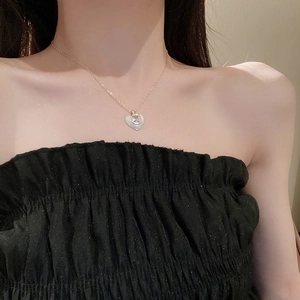 Close-up of golden heart pendant necklace with zircon stone on model's neckline