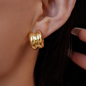 Close-up of golden double-layered C-shaped earrings with a polished mirror finish