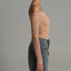 Detail of nude mesh off-shoulder long sleeve top with ruched texture and sheer fabric