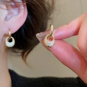 Detail view of gold oval drop earrings featuring a unique hammered texture finish