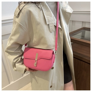 Detail of pink saddle bag with golden vertical metal clasp on a beige trench coat