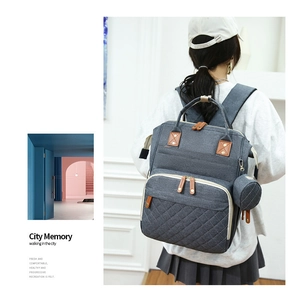 Grey insulated diaper backpack with quilted detail and side pouch on model back