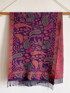Detail view of ethnic cashmere-like shawl with dark purple paisley pattern and tassels
