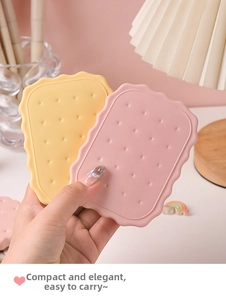 Close-up of portable biscuit-shaped compact mirror with comb in pink and yellow colors