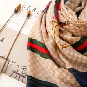 Detail of beige checked scarf with red-green stripes and horsebit pattern motifs
