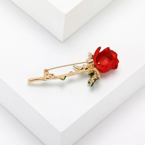 Elegant red enamel rose brooch with gold-plated stem on a clean white display stand
