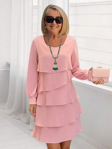 Dettaglio dell'abito rosa a balze con maniche lunghe e collana di perline abbinata