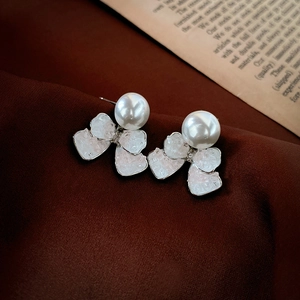 Detail of sweet crystal bow earrings with pearls on a vintage velvet background