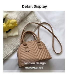 Close-up of beige shell bag with V-shaped quilting and gold metal hardware