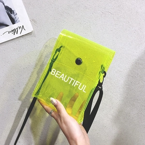 Dettaglio della borsa in PVC trasparente giallo neon con tracolla nera e scritta Beautiful