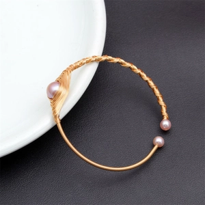 Detail of pink freshwater pearls wrapped in gold wire on an open cuff bracelet