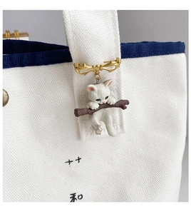 Detail of cute cat hugging a branch brooch pinned on a white canvas bag strap