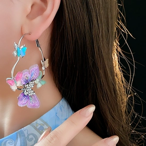 Détail de boucles d'oreilles papillon avec broderie violette et strass scintillants