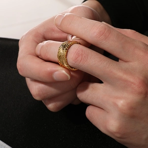 Close-up of golden feather texture design and intricate engraving on a stainless steel ring