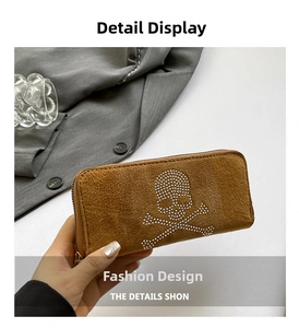 Macro detail of brown suede clutch with crystal skull motif and metallic zipper finish